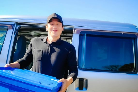 男性配送員がケースを運んでいる